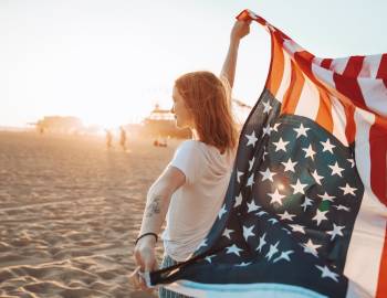 Girl holding an American flag while standing on the beach